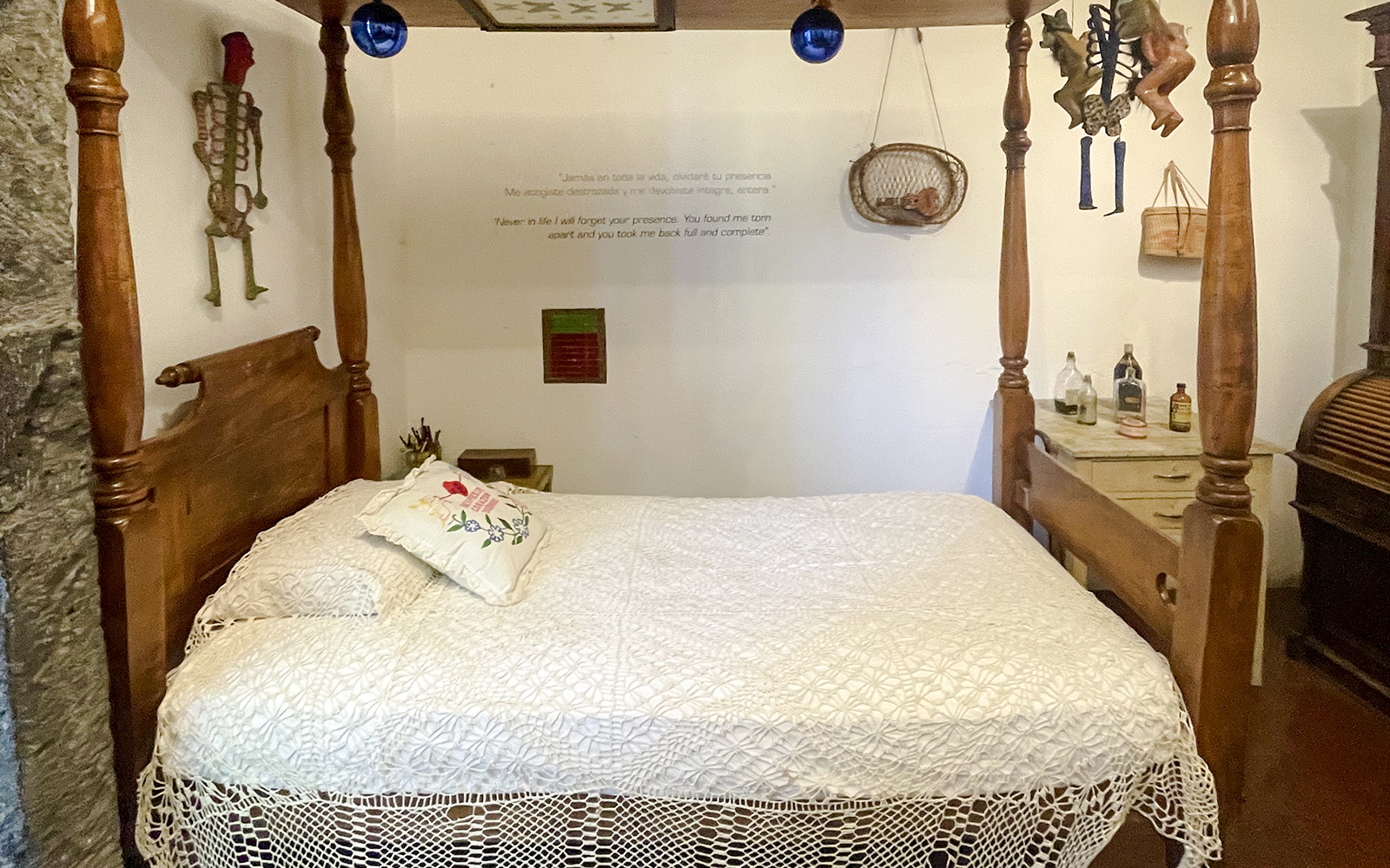 Frida Kahlo Museum bedroom with wooden bed and decorative skeleton on wall.