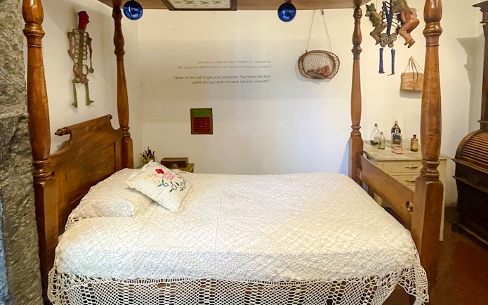 Frida Kahlo Museum bedroom with wooden bed and decorative skeleton on wall.
