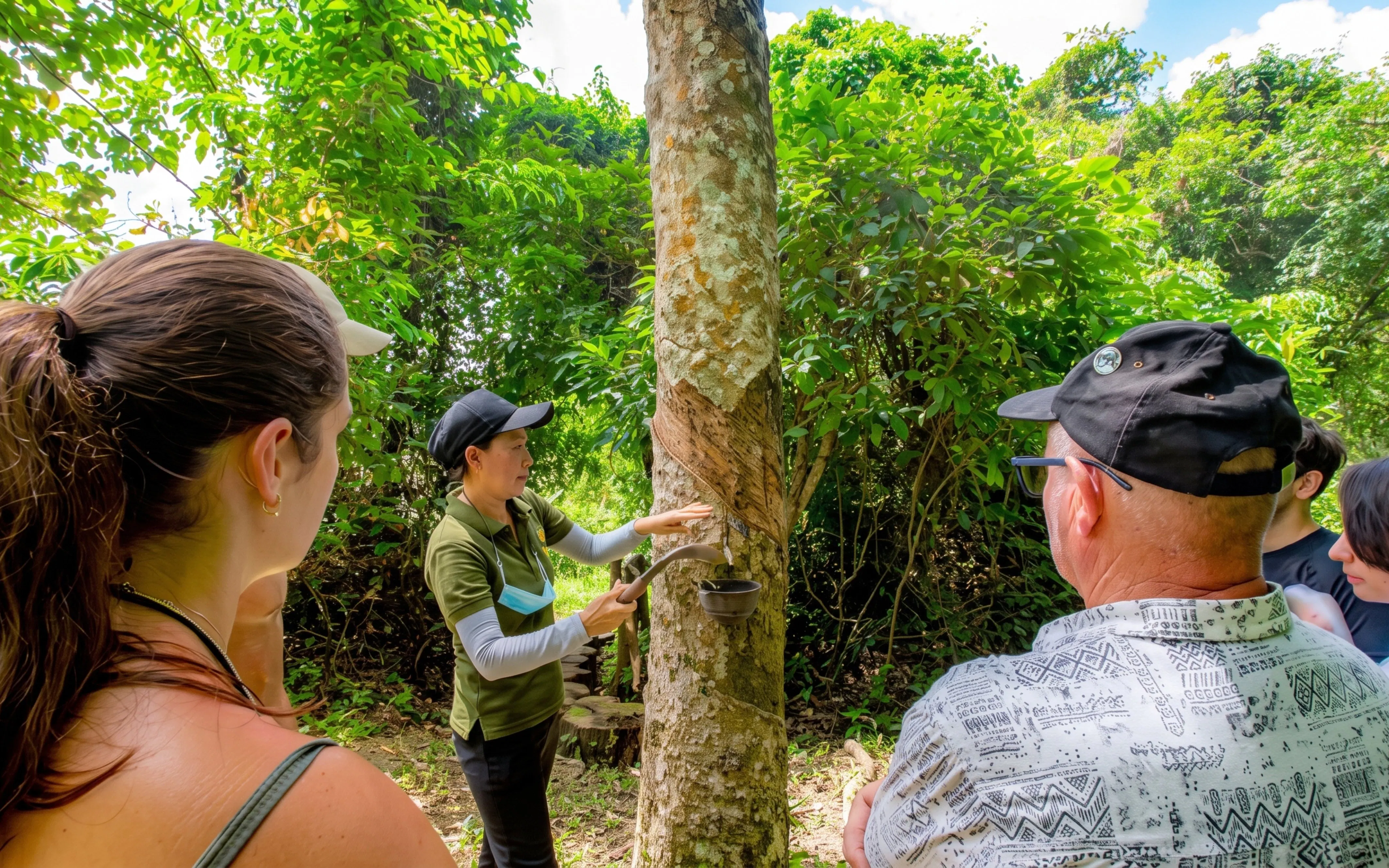 Guide demonstrating rubber tapping to tourists at Phuket Elephant Nature Park.