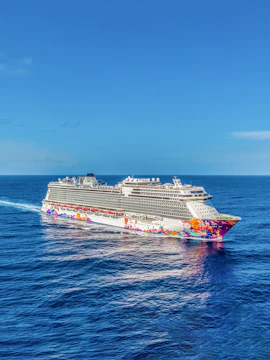 World Dream Cruise ship sailing on open ocean under clear blue sky.