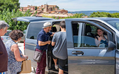 Tourists boarding a minivan near a scenic village in Provence, France.