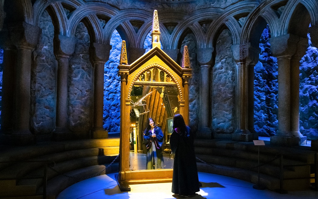 Person in wizard robe looking into the Mirror of Erised at Warner Bros. Studio Tour Tokyo.