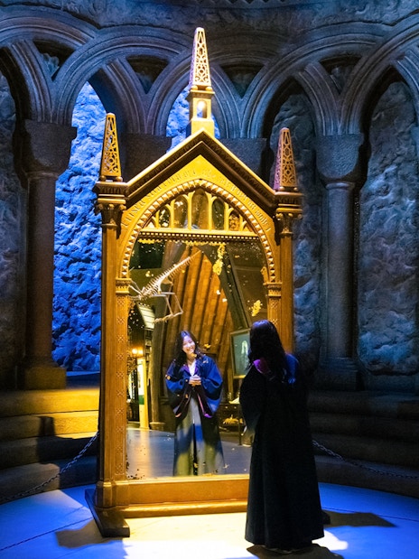 Person in wizard robe looking into the Mirror of Erised at Warner Bros. Studio Tour Tokyo.