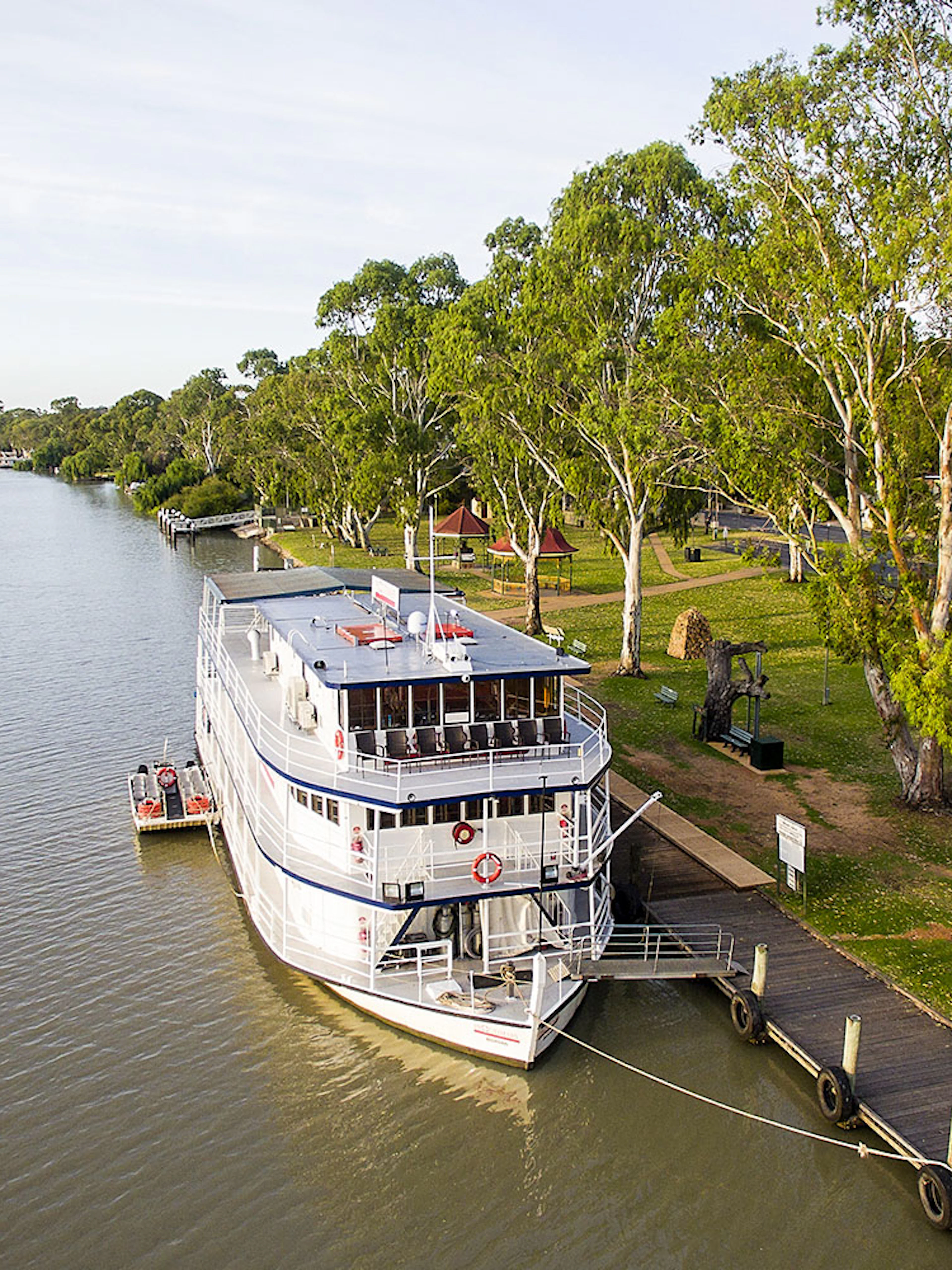 Riverboat docked along the Murray River with lush trees and a wooden pier.