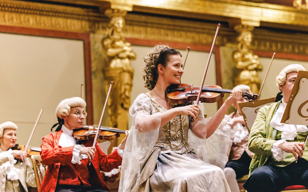 Violinists in period costumes performing at Vienna's Musikverein Golden Hall.