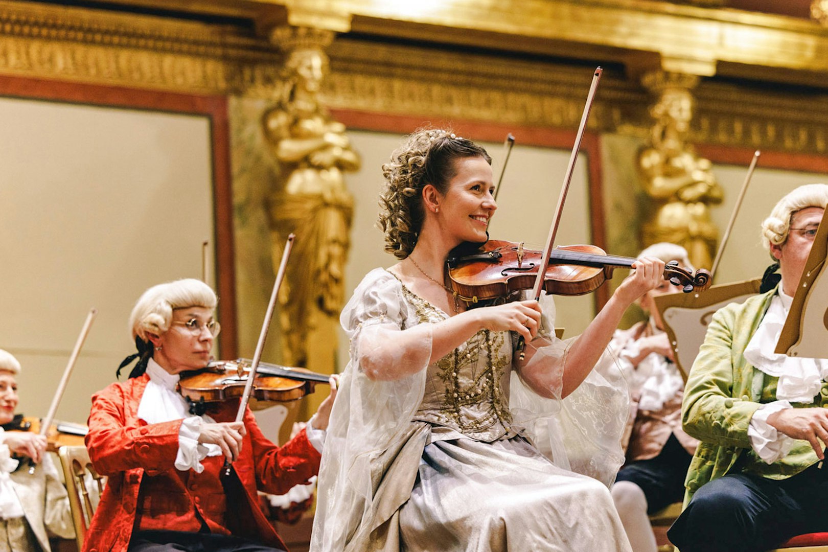 Violinists in period costumes performing at Vienna's Musikverein Golden Hall.