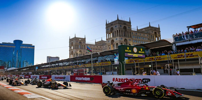 Formula 1 cars racing at Azerbaijan Grand Prix 2026 in Baku cityscape.