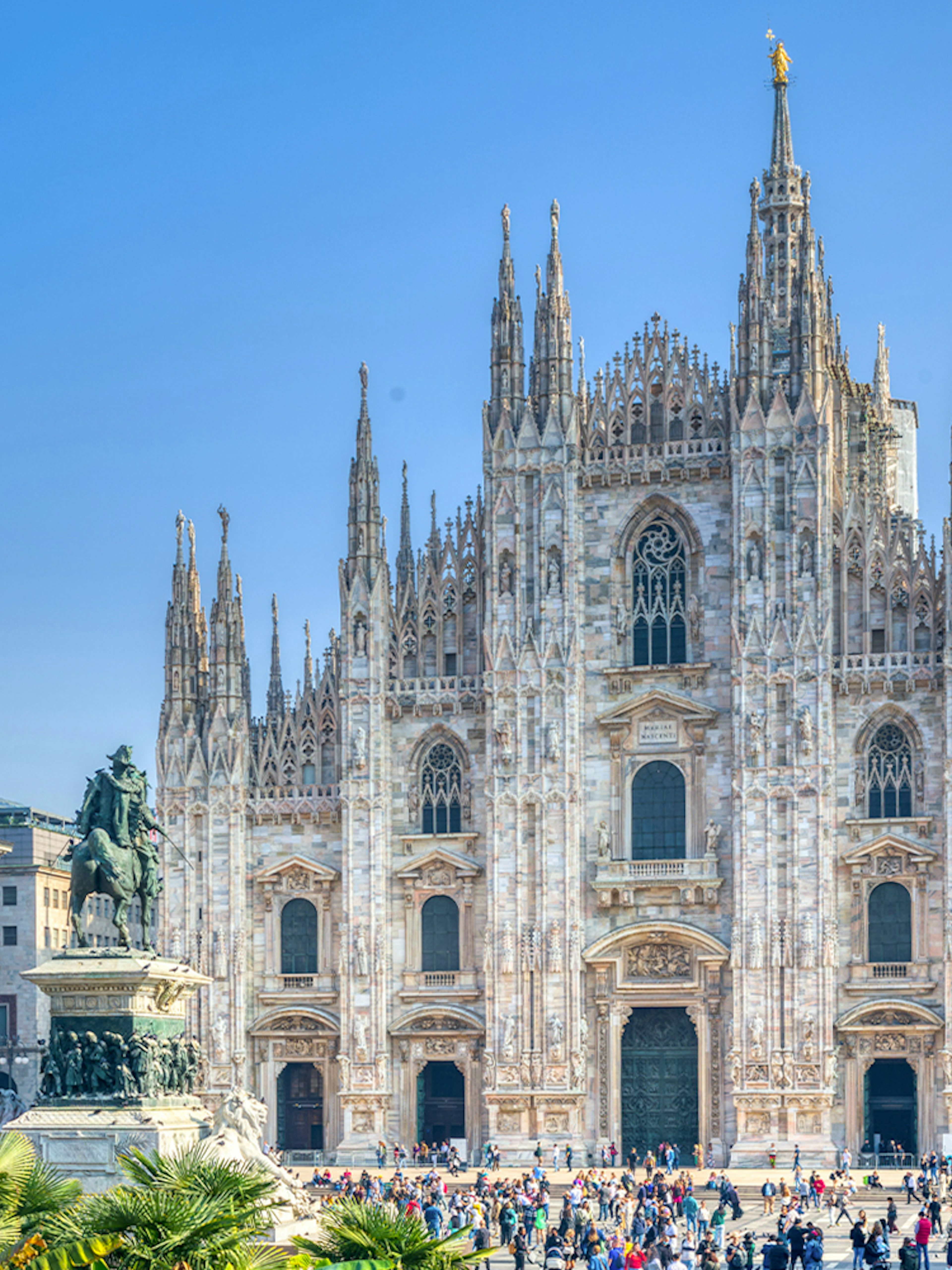 Milan Duomo Cathedral facade with tourists in the foreground.