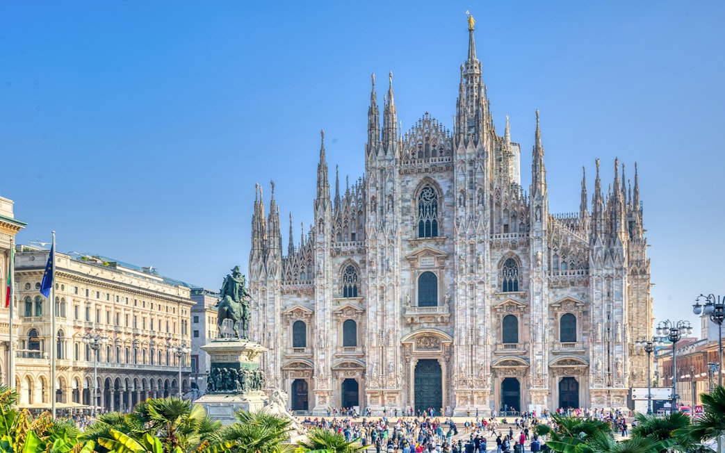 Milan Duomo Cathedral facade with tourists in the foreground.