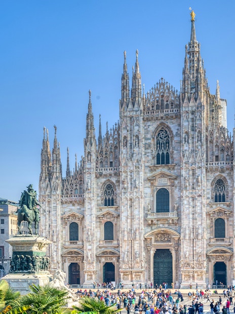 Milan Duomo Cathedral facade with tourists in the foreground.