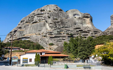 Meteora rock formations with caves and nearby buildings in Greece.