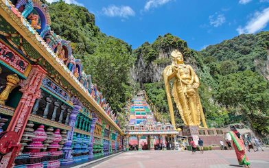 Batu Caves entrance with colorful steps and large golden statue in Kuala Lumpur.