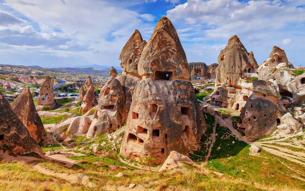 Cappadocia rock formations with ancient cave dwellings under a blue sky.