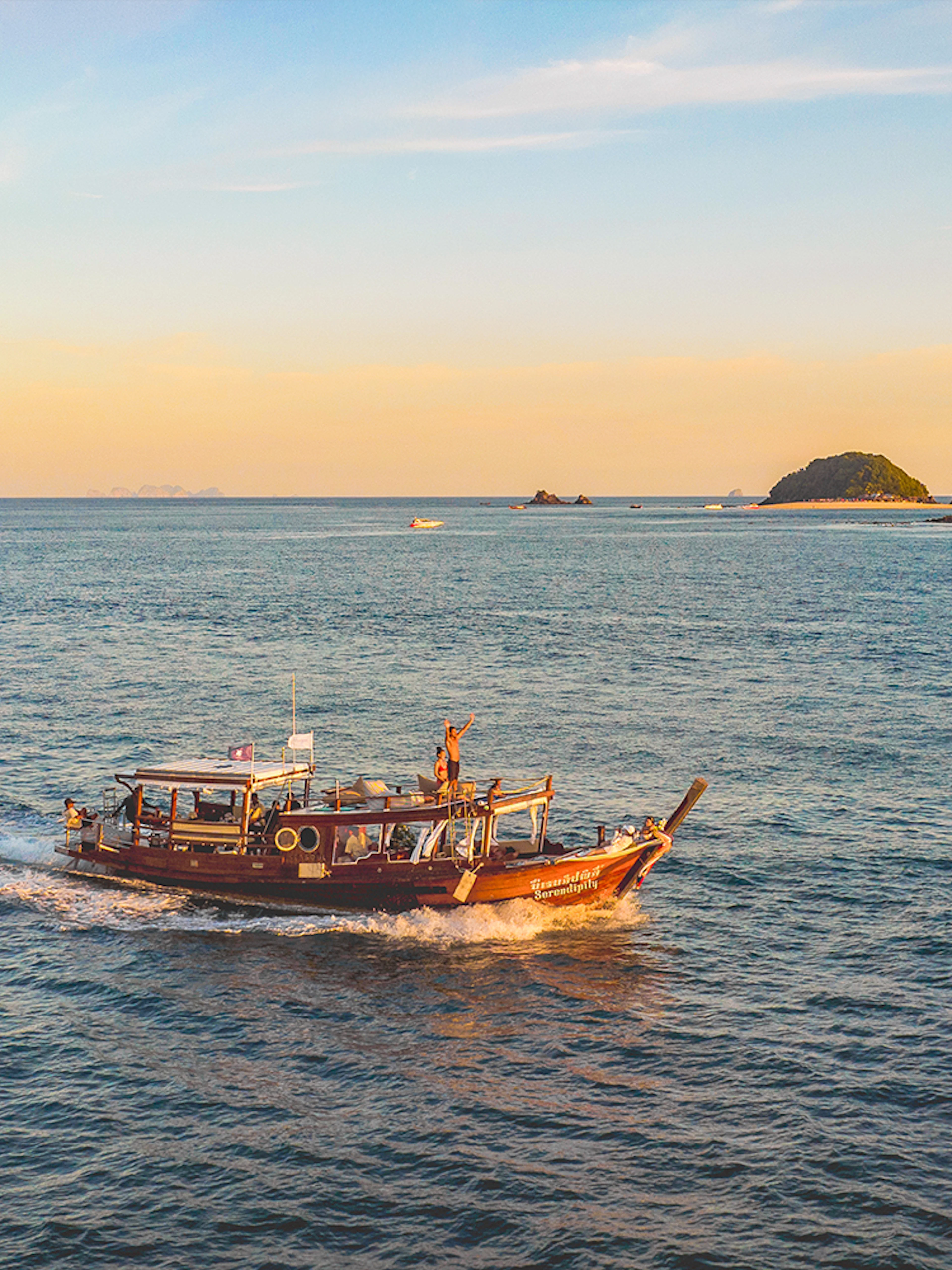 Luxury longtail boat cruise at sunset near Krabi with people on board.