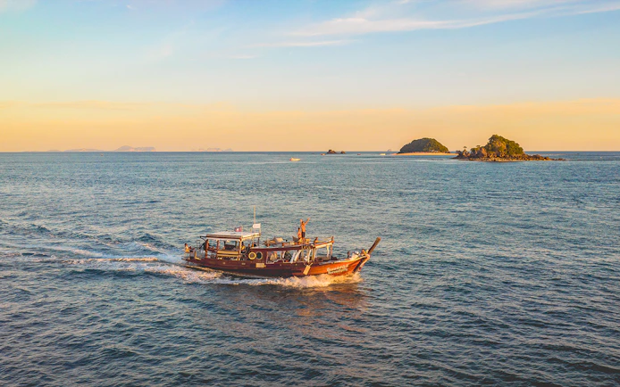 Luxury longtail boat cruise at sunset near Krabi with people on board.