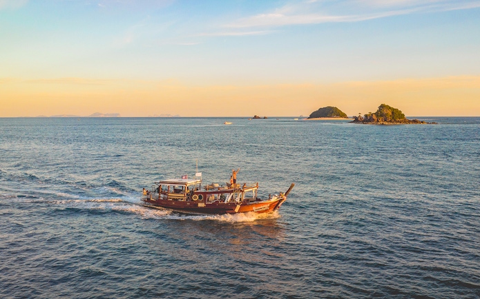 Luxury longtail boat cruise at sunset near Krabi with people on board.