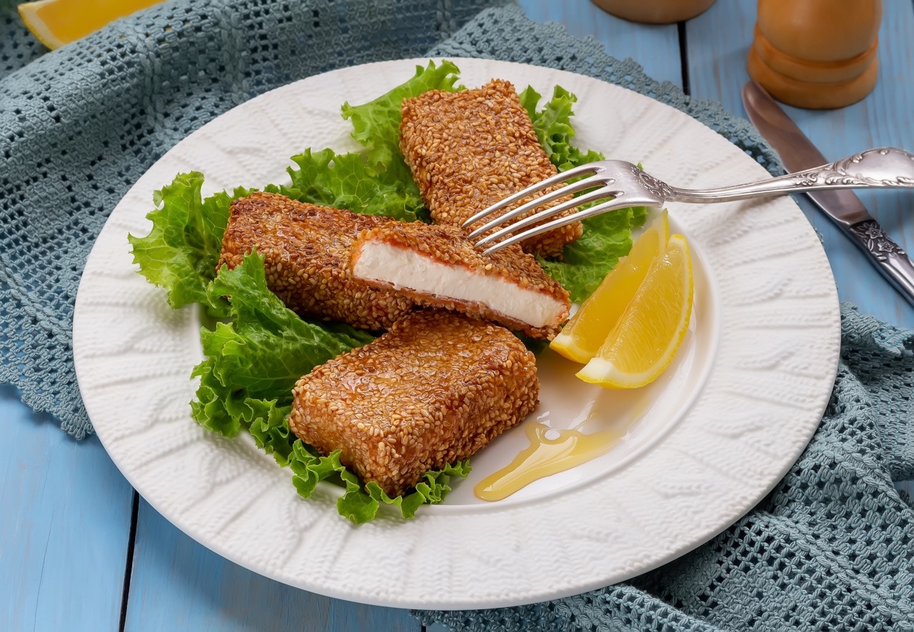 Saganaki with lemon wedges on a plate in Athens, Greece.