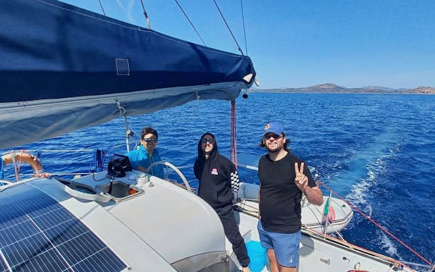 Catamaran tour group sailing near Tavolara Island, clear blue sea in the background.