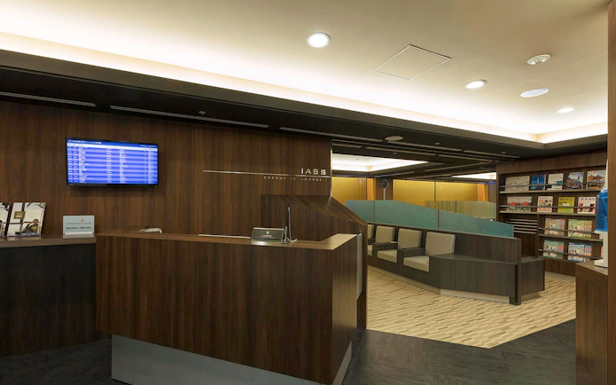 Waiting area at Narita International Airport Terminal 1 lounge with seating and flight information display.