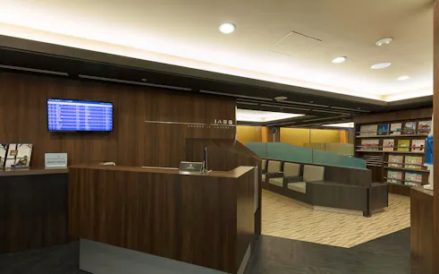 Waiting area at Narita International Airport Terminal 1 lounge with seating and flight information display.