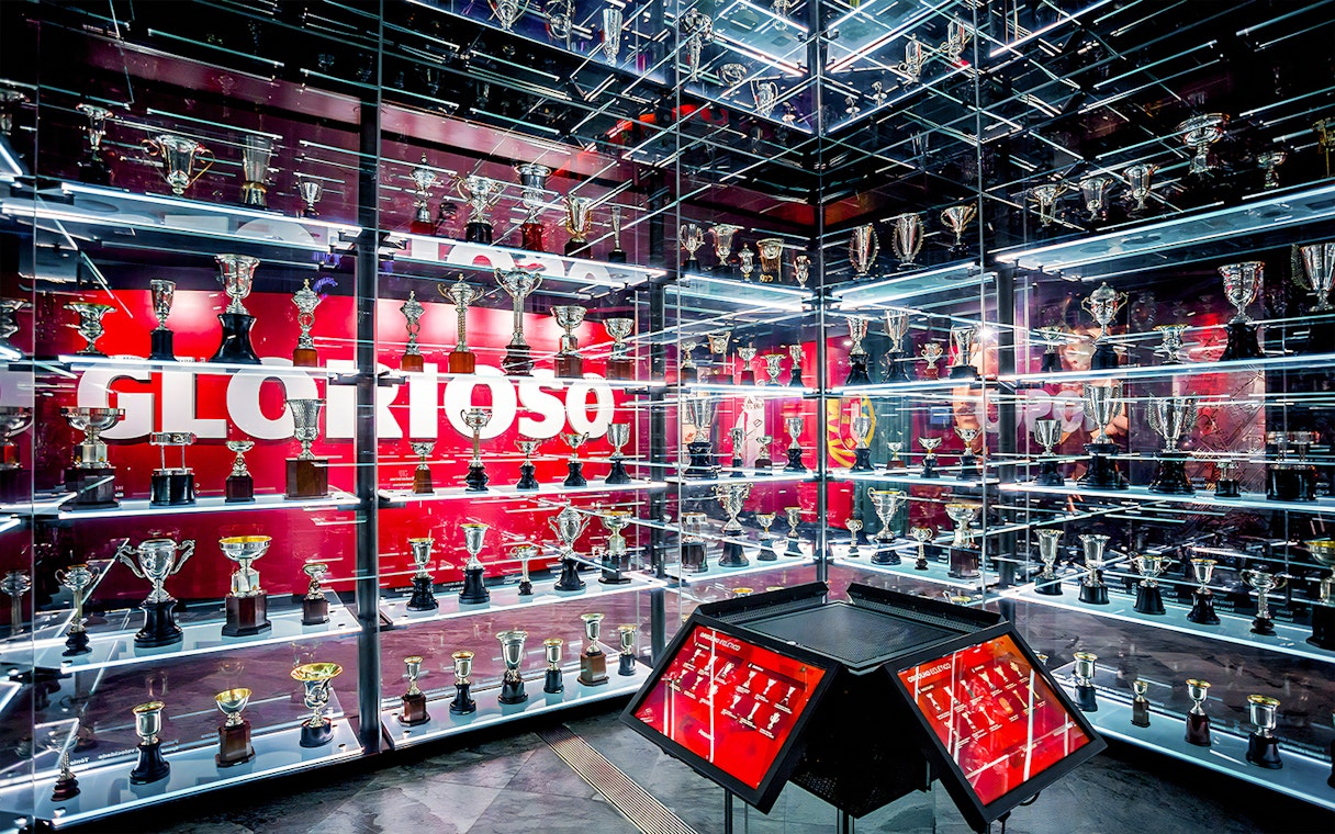 Benfica Stadium museum trophy display with numerous awards on shelves.