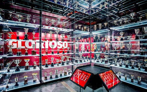 Benfica Stadium museum trophy display with numerous awards on shelves.