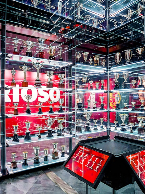 Benfica Stadium museum trophy display with numerous awards on shelves.