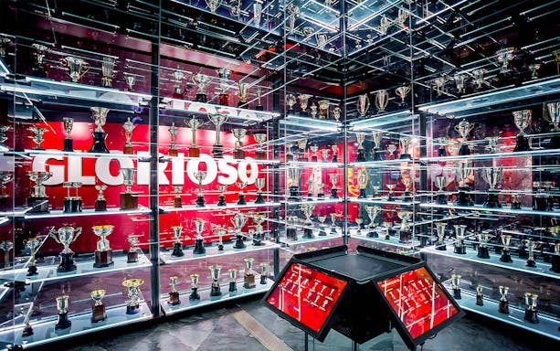 Benfica Stadium museum trophy display with numerous awards on shelves.