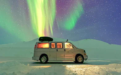 Minivan under Northern Lights during premium small group tour.