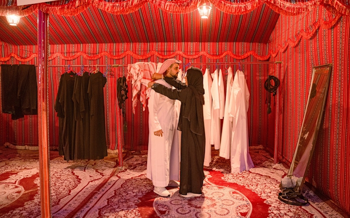 People dressing in traditional Arab attire inside a tent during a desert safari in Abu Dhabi.