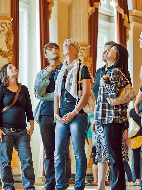 Tour group listening to a guide inside the ornate Semperoper, Dresden.
