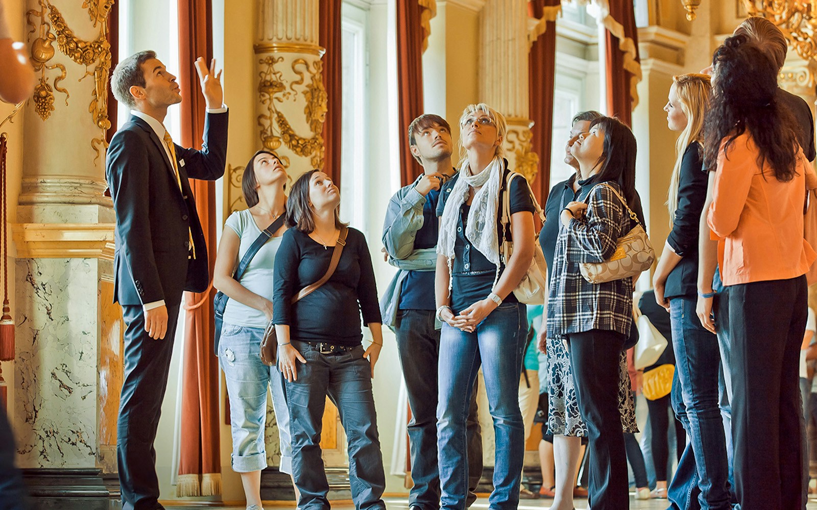 Tour group listening to a guide inside the ornate Semperoper, Dresden.