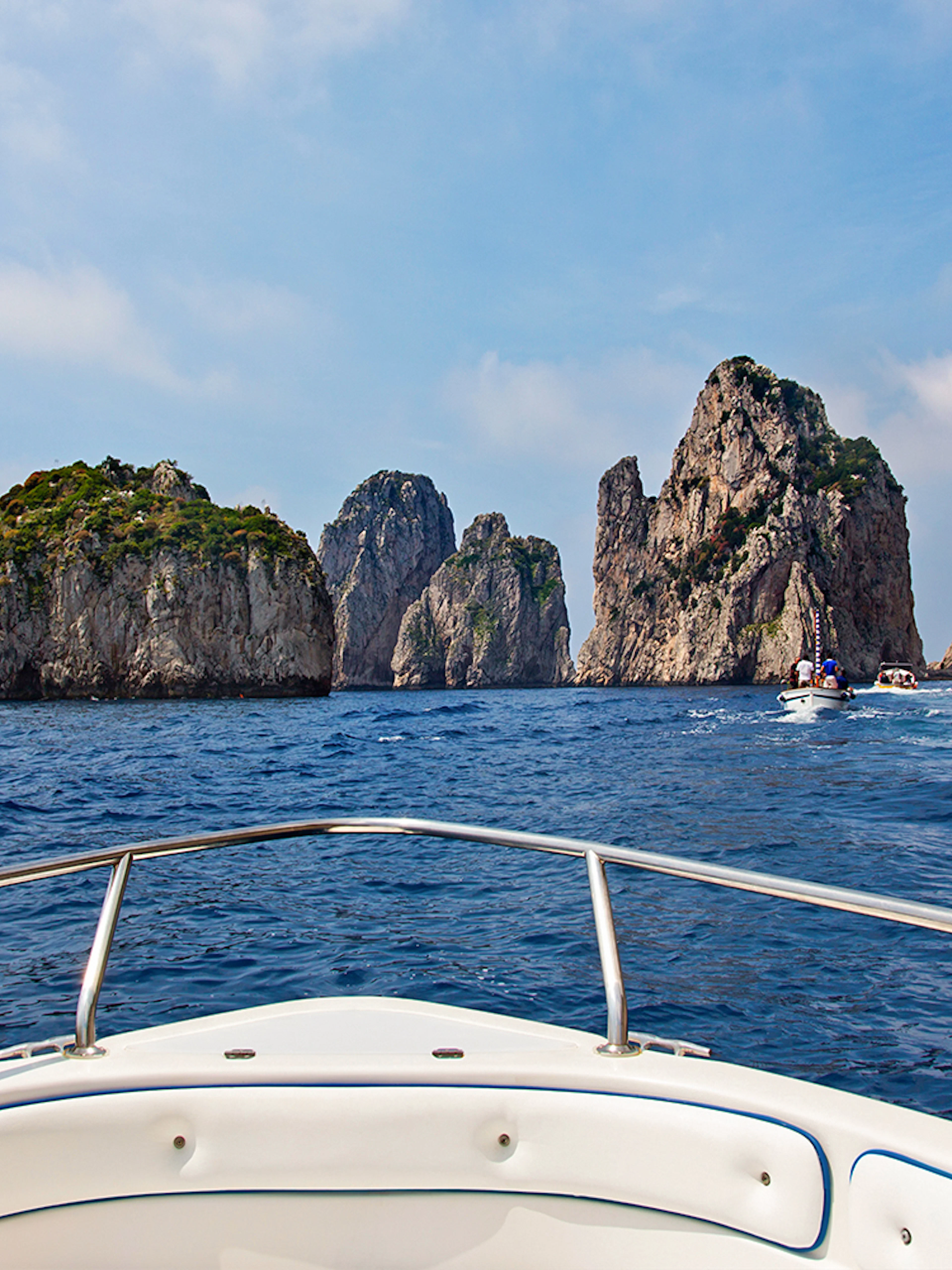 Boat approaching Faraglioni rocks on Capri tour from Rome.