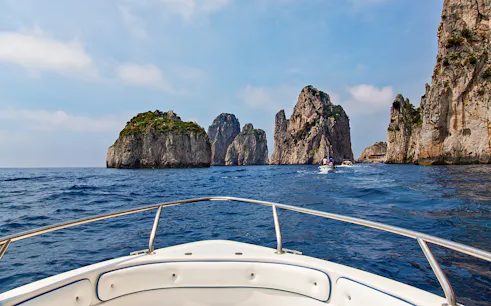 Boat approaching Faraglioni rocks on Capri tour from Rome.