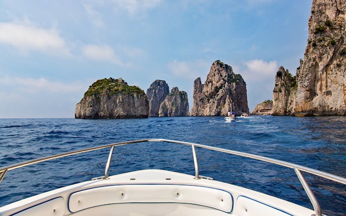 Boat approaching Faraglioni rocks on Capri tour from Rome.