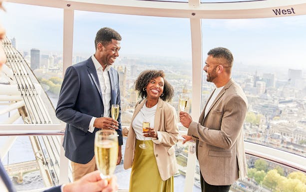 Friends enjoying drinks in a London Eye capsule with city views.