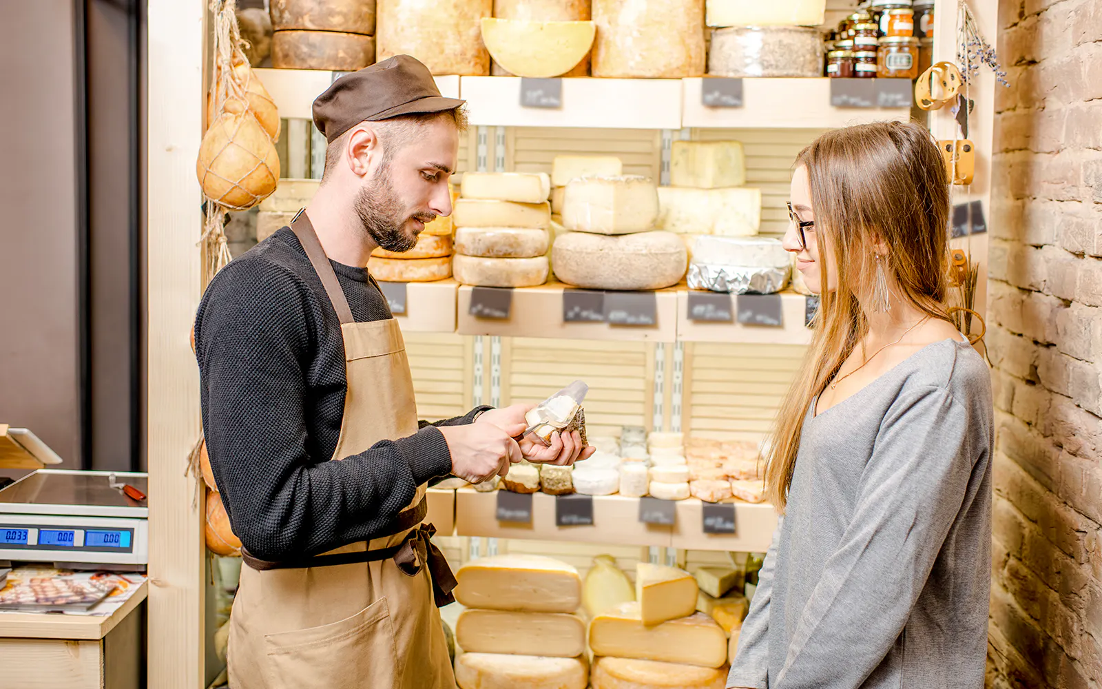 Server offering cheese sample to guest at Cheese Museum in Paris.
