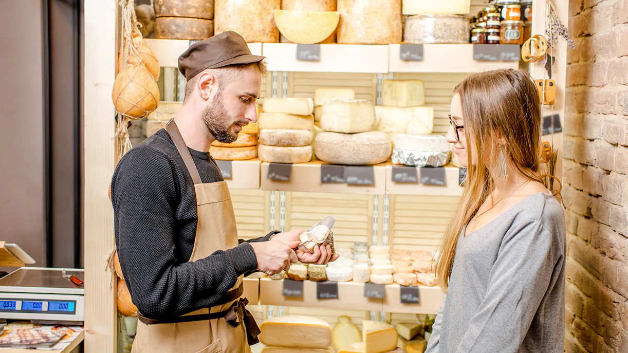 Server offering cheese sample to guest at Cheese Museum in Paris.