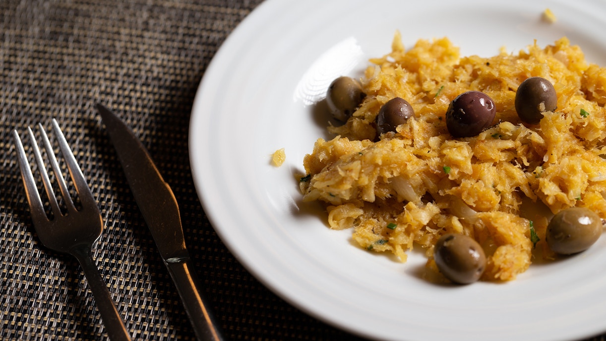 Bacalhau à Brás with olives on a white plate, Portuguese cuisine.