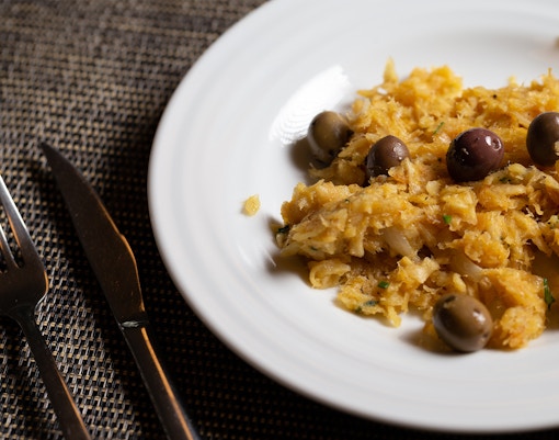 Bacalhau à Brás with olives on a white plate, Portuguese cuisine.