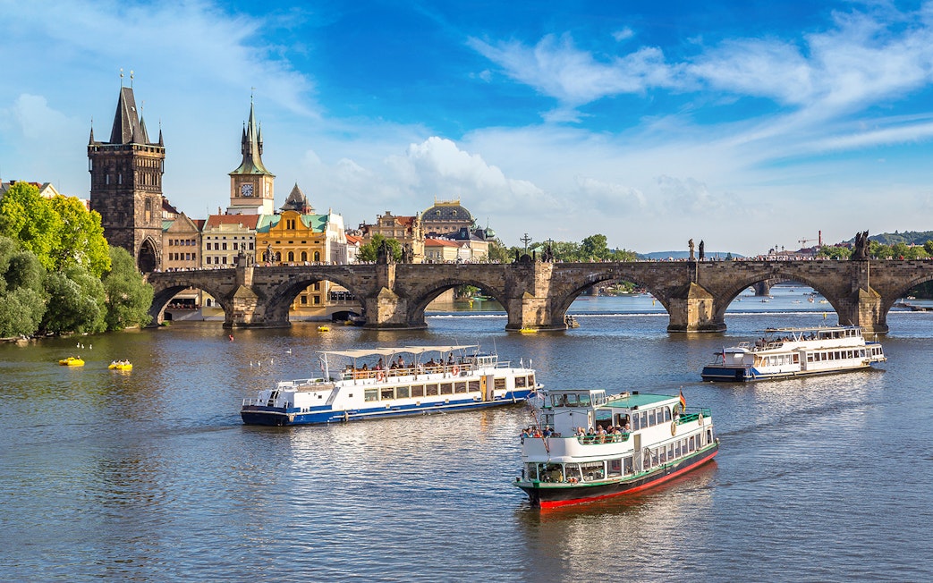 Cruise boats on the Vltava River with Charles Bridge in Prague.