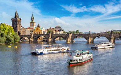 Cruise boats on the Vltava River with Charles Bridge in Prague.