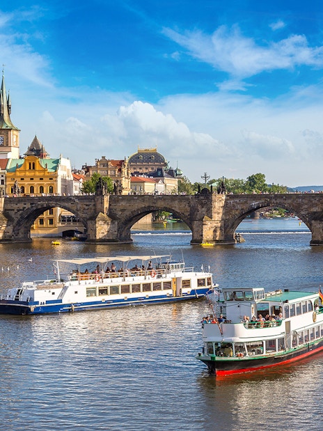 Cruise boats on the Vltava River with Charles Bridge in Prague.