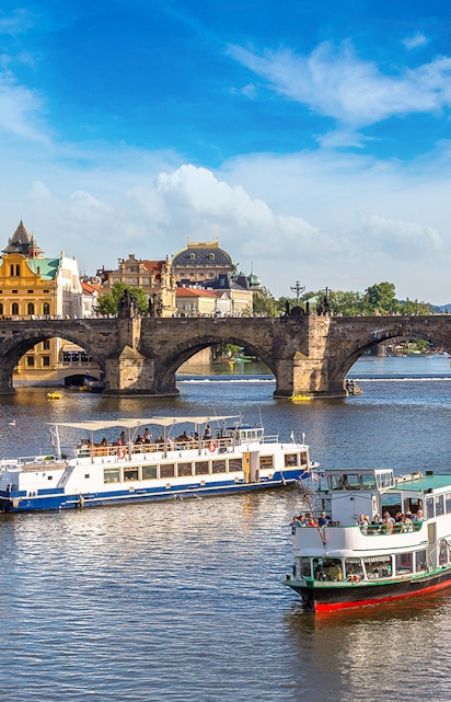 Cruise boats on the Vltava River with Charles Bridge in Prague.