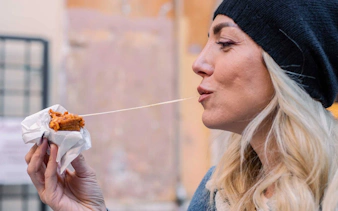 Woman enjoying a cheesy snack outdoors.