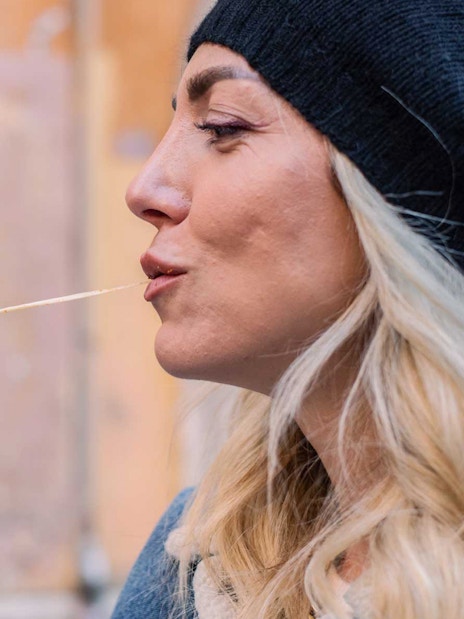 Woman enjoying a cheesy snack outdoors.