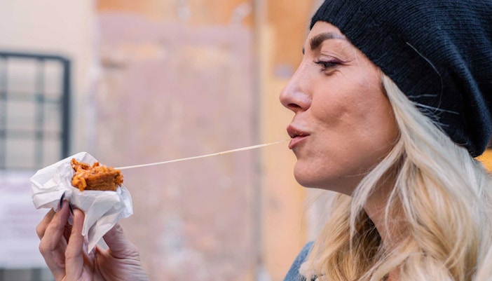 Woman enjoying a cheesy snack outdoors.