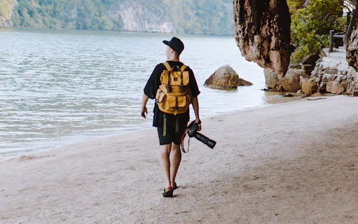 Person walking on a sandy beach with a camera, Phang Nga Bay, Phuket.