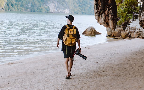 Person walking on a sandy beach with a camera, Phang Nga Bay, Phuket.