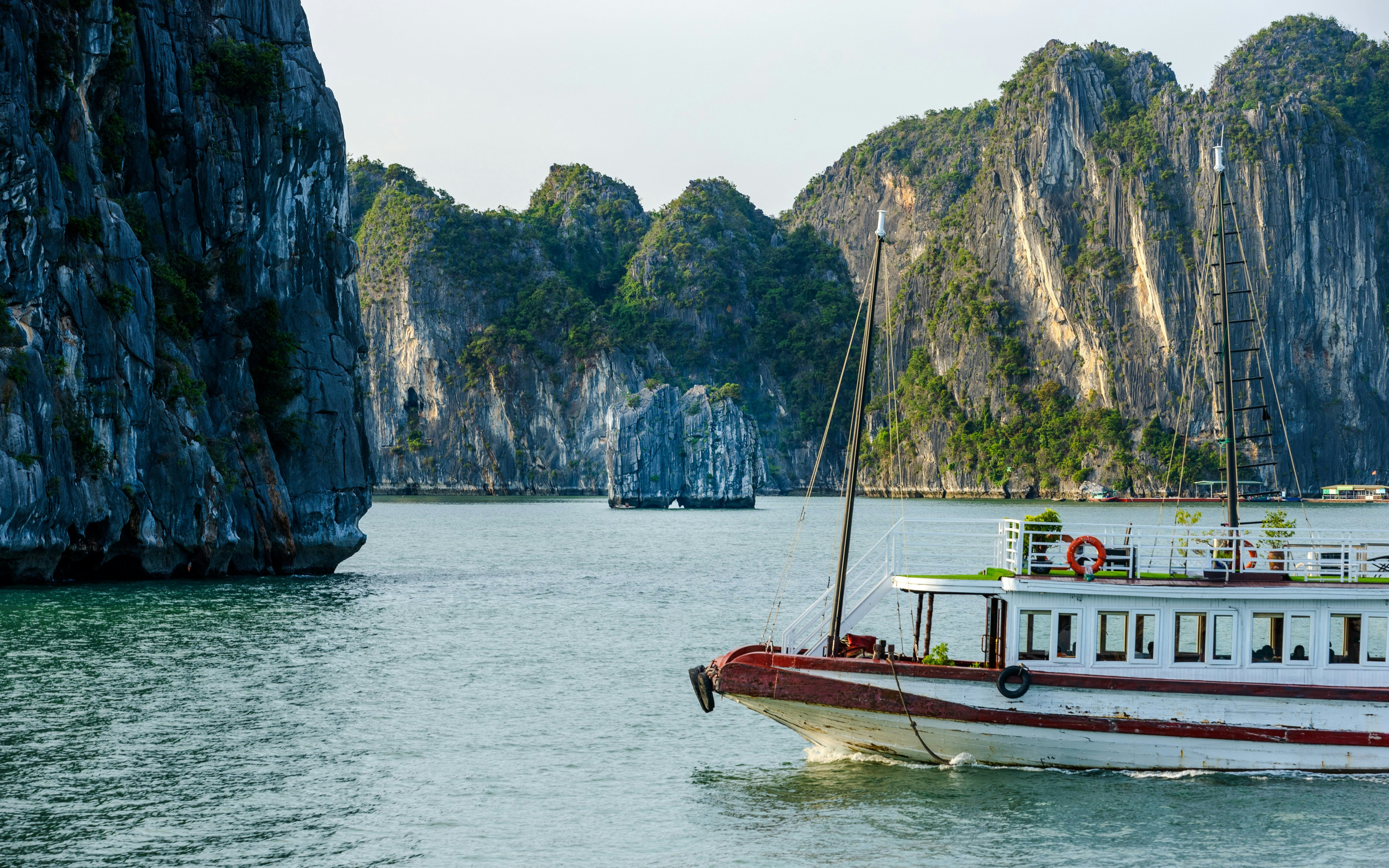 Cruise boat near limestone cliffs at Dinh Huong Island, Halong Bay, Vietnam.